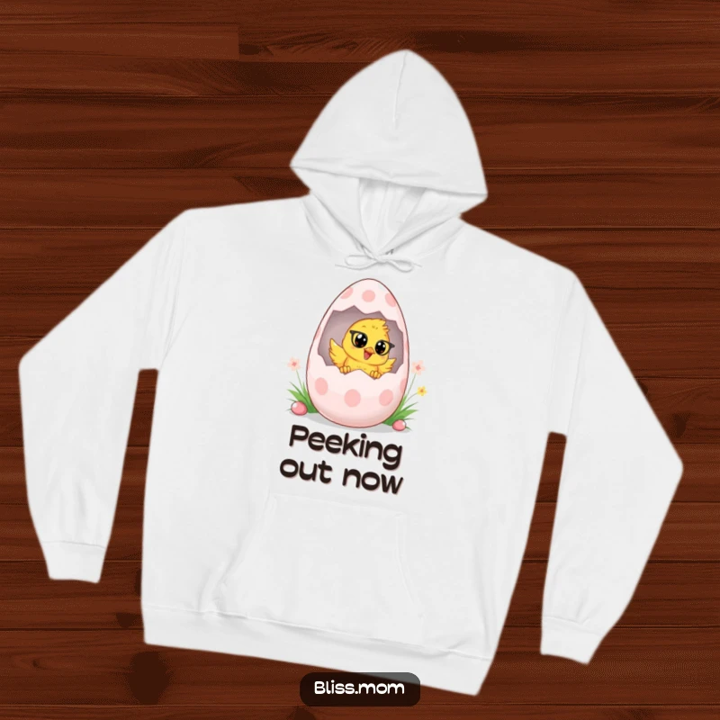 Funny Chick Mom Hoodie, depicting a cheerful chick mom peeking out of a giant Easter egg, ideal for cozy spring days. A great gift.