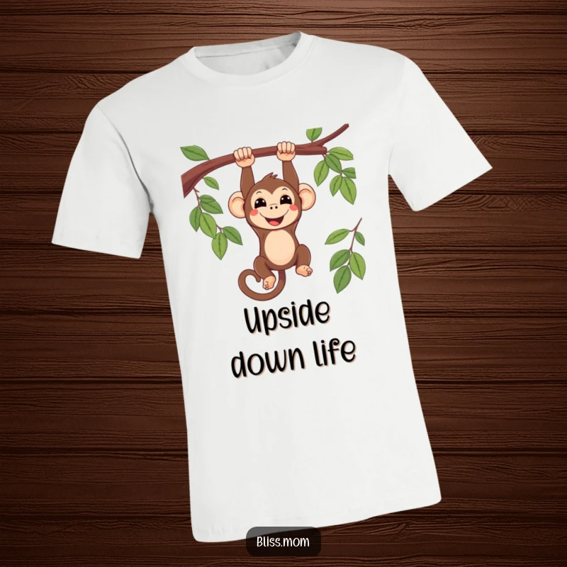 Funny smiling kawaii monkey hanging upside down from a tree branch, on a soft cotton t-shirt, conveying playful energy.
